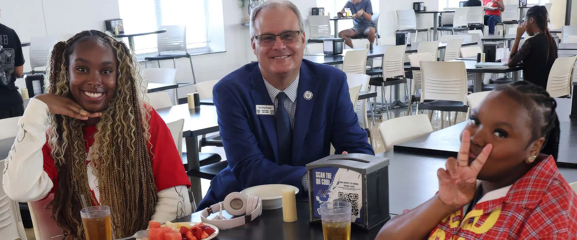 Students and President sitting in dining hall together