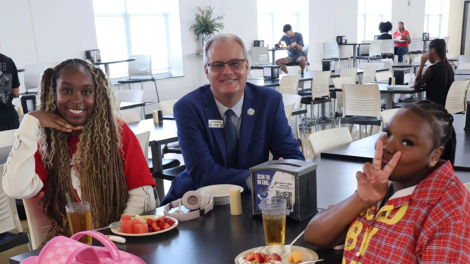 Students and President sitting in dining hall together